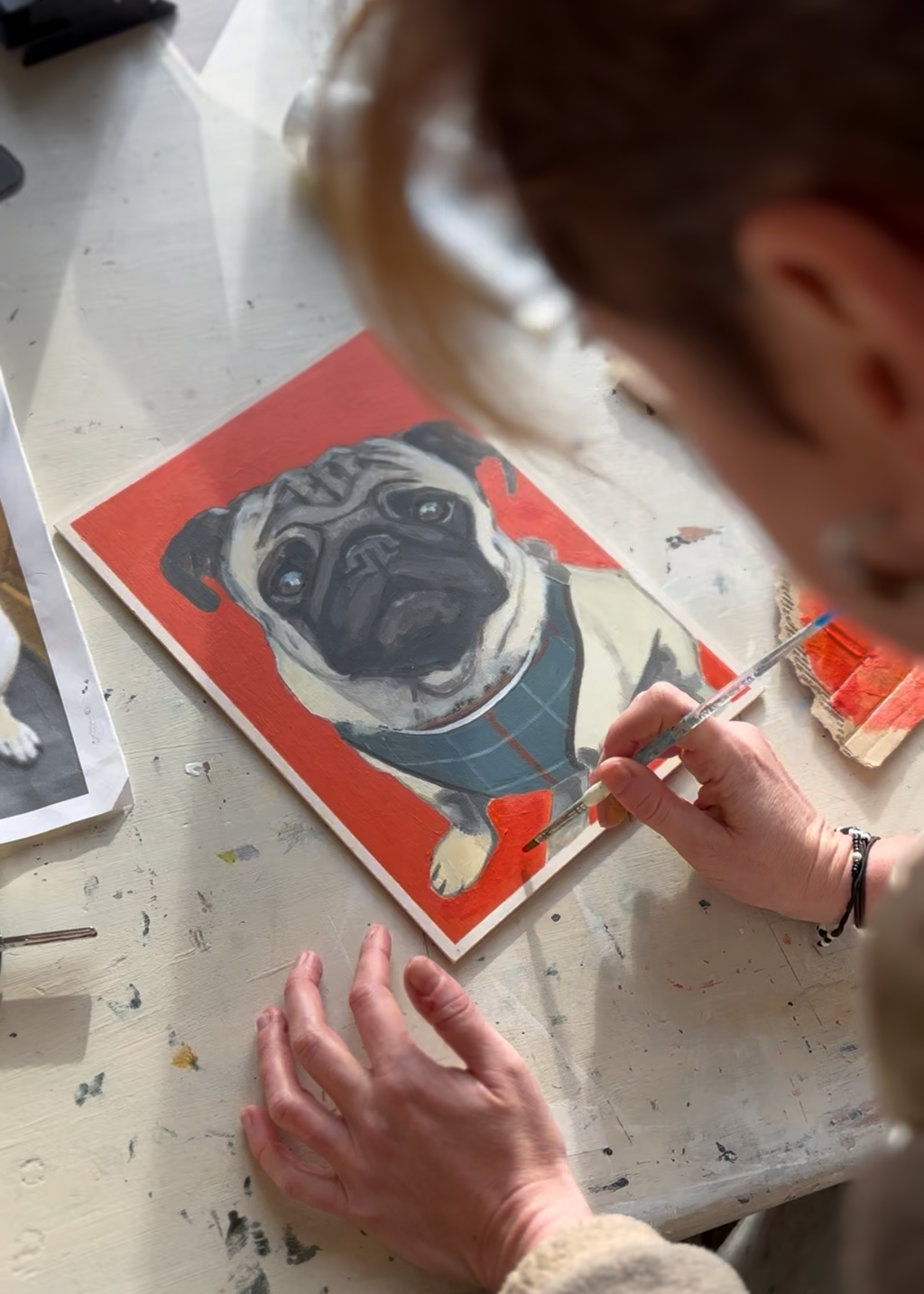 Artist Helen Robotham Vasquez creating a custom, hand-painted pet portrait of pug Cilla, in her Wirral studio.